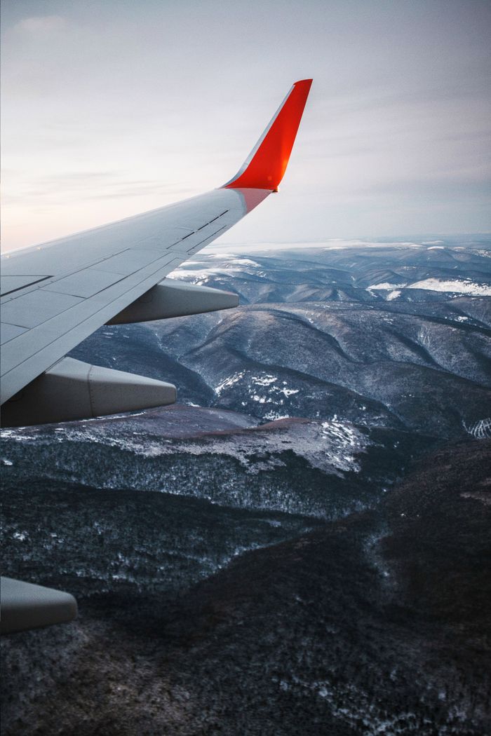 services-03 Scenic aerial view of a mountain range covered in snow, seen from an airplane wing.
